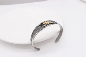 Detail of vintage steel feather cuff bracelet with golden star on white display plate