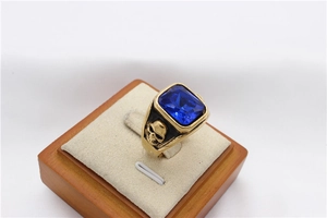 Detailed close-up of a vintage men's gold ring with a blue gemstone and skull carvings