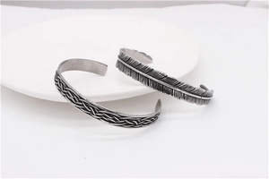 Detail of vintage silver feather and braided rope bangle set on a white round base