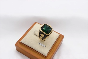 Detailed view of men's vintage gold skull ring with a large square green gemstone