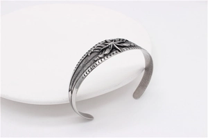 Detailed close-up of retro stainless steel cuff bracelet with feather patterns and star motif