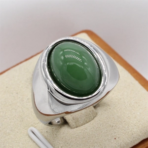 Bague vintage en acier poli avec pierre ovale verte sur un support à bijoux