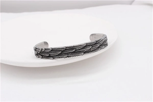 Detailed macro shot of vintage feather pattern on a titanium steel cuff bracelet