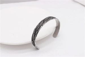 Detailed view of vintage steel feather cuff bracelet with retro oxidized finish