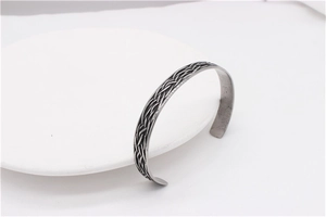 Close-up of retro silver feather steel cuff bracelet with intricate woven texture detail