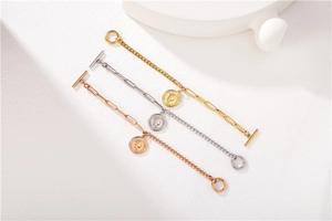 Détail de bracelets à pendentif pièce en or, argent et or rose avec fermoirs à bascule