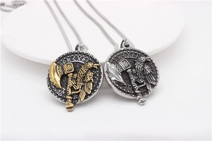 Macro detail of Nordic Viking axe and raven relief engraved on round steel pendant