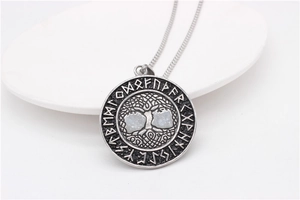 Detail of vintage Tree of Life pendant with Nordic runes on a white ceramic plate