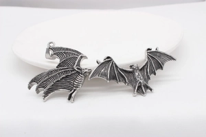 Detail showing two vintage gothic bat wing pendants in retro silver finish on white ceramic