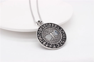 Macro view of vintage Viking Yggdrasil pendant with rune symbols on white ceramic surface