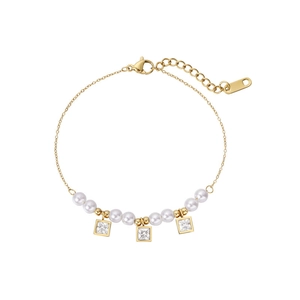 Détail du bracelet de perles dorées avec breloques en zircone sur une fine chaîne en O