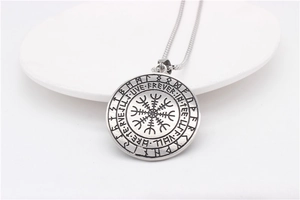 Detailed close-up of retro silver Viking Vegvisir pendant with runes on ceramic plate