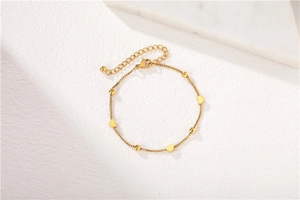 Close-up of golden box chain bracelet with heart charms and adjustable lobster clasp
