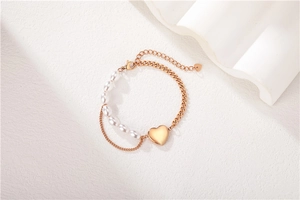 Detail of rose gold double layer bracelet with pearls and a heart-shaped pendant