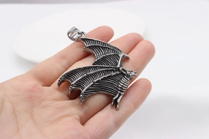 Detailed close-up of a large vintage gothic bat wing pendant held in hand for size comparison