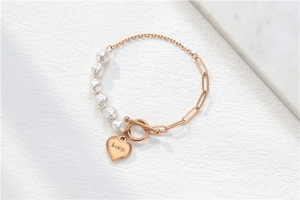 Makro-Detail von Roségold-Herzanhänger mit Love-Gravur und barocker Perlenkette