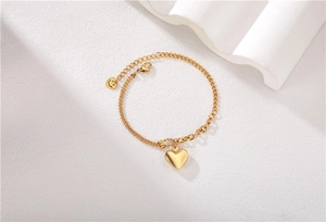 Dettaglio di un bracciale dorato con ciondolo a cuore, doppia catena e sorriso