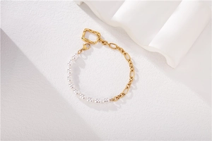 Détail d'un bracelet élégant avec demi-perles et chaîne dorée irrégulière sur blanc