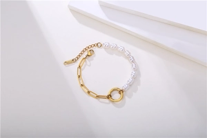 Detail of elegant gold paperclip chain and white pearl bracelet with S925 sterling silver tag