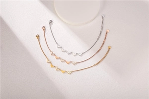 Detailed view of three heart-shaped titanium steel bracelets in gold, silver, and rose gold