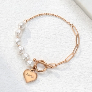 Elegantes Perlenarmband mit Kette, Herzanhänger und Love-Gravur auf steinernem Untergrund