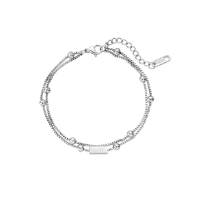 Detailed macro view of double-layer silver chain bracelet with Lucky engraved charm
