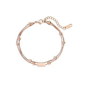 Detail of rose gold double-layered box chain bracelet with round beads and Lucky charm