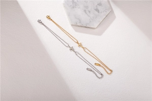 Détail de bracelets perlés avec pendentif croix en or et argent avec fermoir ajustable