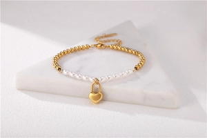 Detailed shot of gold heart lock pendant and fresh water pearls on a stylish bracelet