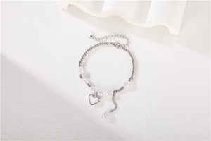 Détail du bracelet en perles argentées avec perles blanches et pendentif cœur poli
