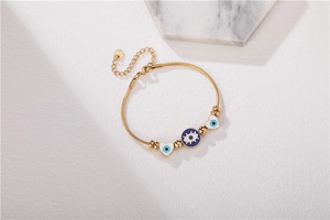 Détail macro du bracelet chaîne serpent doré avec breloques œil bleu et cœurs