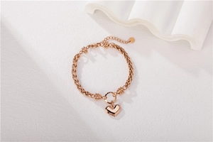 Detail of rose gold heart pendant bracelet with woven metal chain and lobster clasp