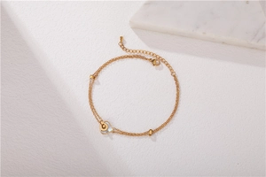 Détail du bracelet double couche doré avec pendentif cœur en nacre et perles