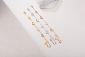 Detailed view of three heart charm bracelets in gold, silver and rose gold finishes