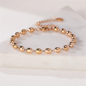 Elegante bracciale da donna con perle ovali in oro rosa su una superficie di marmo