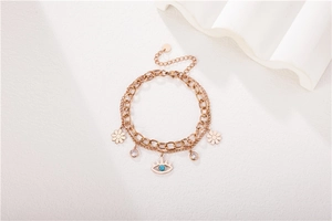 Détail du bracelet multicouche en or rose avec pendentifs oeil protecteur et marguerite