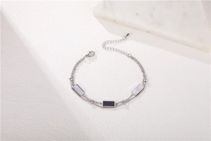 Détail du bracelet double chaîne avec pendentifs rectangulaires en nacre et fermoir homard