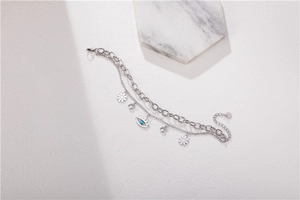 Détail du bracelet en acier inoxydable argenté avec breloques œil et marguerite