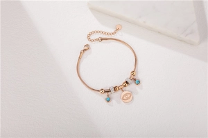 Détail du bracelet chaîne serpent or rose avec breloque œil et perles bleues