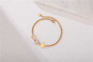 Detailed close-up of a gold heart charm bracelet with sparkling crystals and lobster clasp