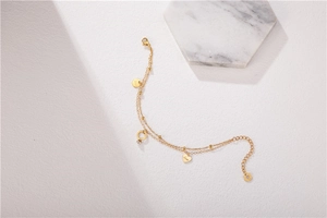 Detail of gold double-layer chain bracelet with heart charms and love engraving