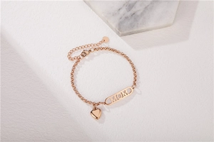 Detail of rose gold MOM bracelet with delicate heart charm on marble texture backdrop