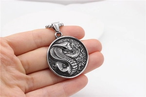 Macro view of retro stainless steel round cobra pendant with detailed silver snake relief