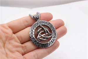 Macro shot of Viking runes and Triquetra knot detail on a vintage titanium steel pendant
