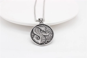 Detailed close-up of retro stainless steel cobra pendant with embossed scales texture
