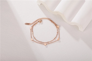 Detail of rose gold double-layer heart bracelet with lobster clasp on white texture