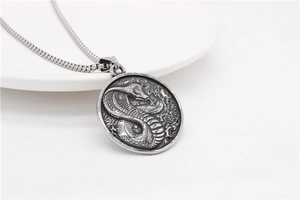 Macro shot of silver cobra medallion pendant showing detailed scales and punk style metal