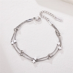 Double-layered stainless steel star bracelet with polished charms on a white stone surface
