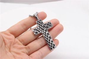 Close-up of vintage square mosaic cross pendant in durable titanium steel held by hand