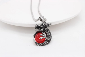 Close-up of retro dragon pendant with red bead and detailed engraving on snake chain